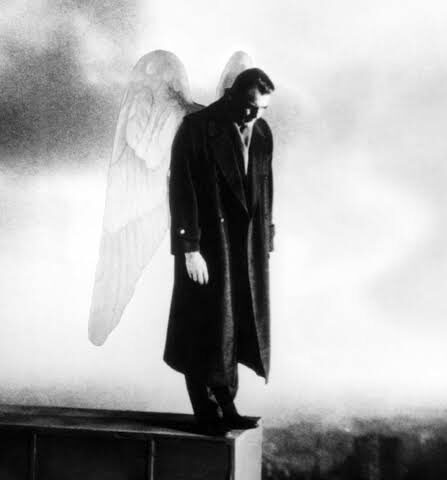 An illustration of a man standing on a ledge in all black with a pair of grey and white angel wings. He looks down.